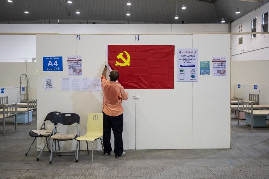 A worker removes a Communist Party flag as workers demolish installations at Wuhan's makeshift hospital built to treat patients infected by the Covid-19 coronavirus in China's Hubei province on 29 July 2020. (STR/AFP)