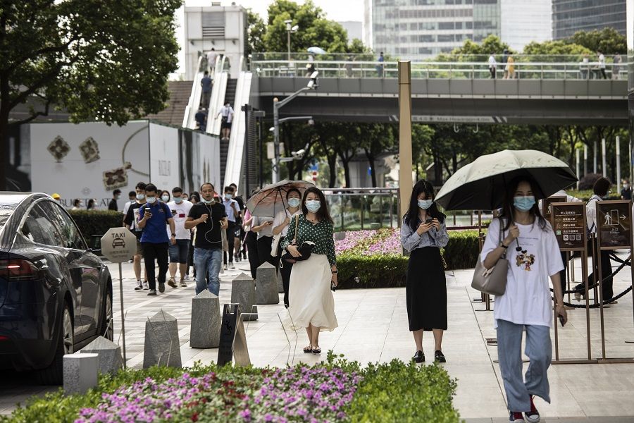 Pedestrians wearing protective masks make their way through the financial district during the morning rush hour in Shanghai, China, 6 August 2021. (Qilai Shen/Bloomberg)