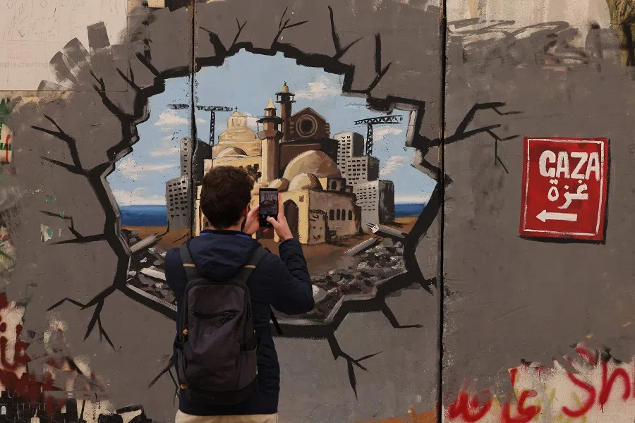 A man takes a picture of graffiti representing the reconstruction of Gaza, on a section of Israel’s separation barrier, in Bethlehem in the occupied West Bank on 12 February 2025.