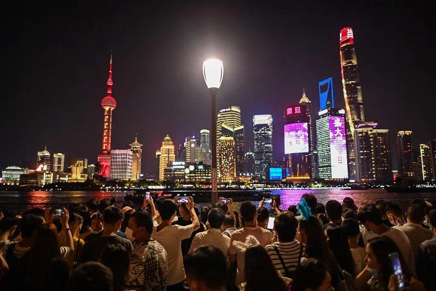 People take pictures of Shanghai's skyline from the Bund along the Huangpu River in Shanghai, China, on 1 October 2021. (Hector Retamal/AFP)