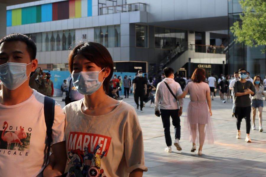 People wearing face masks following the coronavirus outbreak walk at a shopping complex in Beijing, China, on 24 May 2020. (Florence Lo/Reuters)