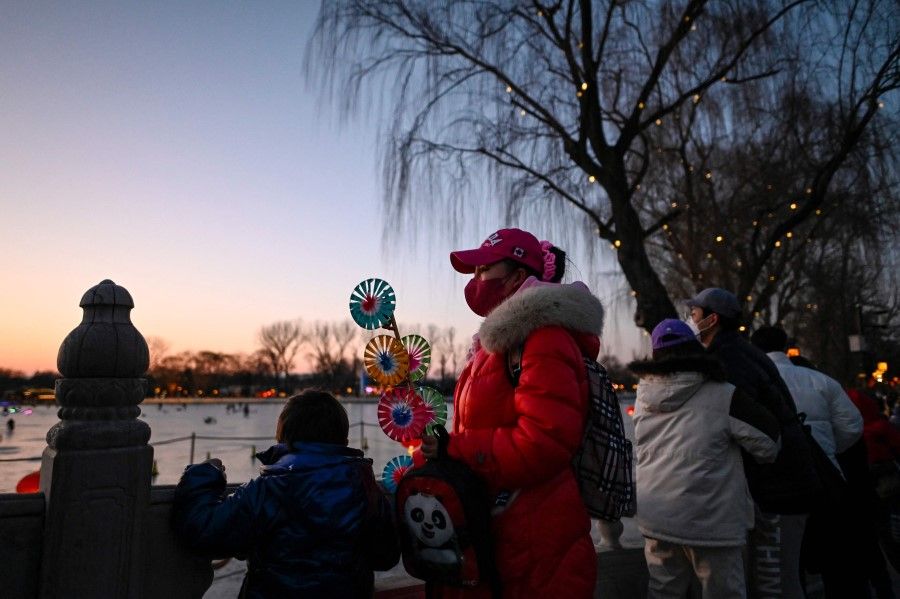 A woman holds a wind-wheel during sunset on the second day of the Lunar New Year of the Tiger in Beijing on 2 February 2022. (Jade Gao/AFP)