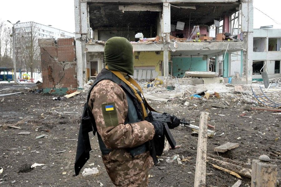 A member of the Ukrainian Territorial Defence Forces looks at destructions following a shelling in Ukraine's second biggest city of Kharkiv on 8 March 2022. (Sergey Bobok/AFP)