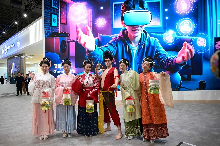 China Mobile stand hosts pose during the MWC (Mobile World Congress), the world’s biggest mobile fair, in Barcelona on 3 March 2025. Surrounded by investment and innovation projects, the Mobile World Congress (MWC) kicks off today in Barcelona amid a context of euphoria but also tensions over artificial intelligence (AI), whose rapid advancement is shaking up the tech sector. (Josep Lago/AFP)