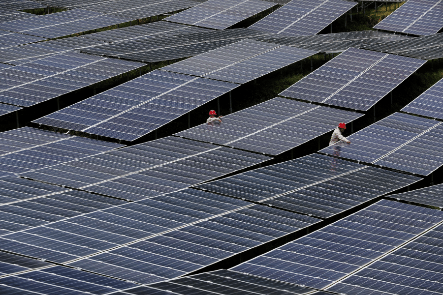 Workers check solar panels at a photovoltaic power station in Chongqing, China, 27 July 2018. (Reuters)