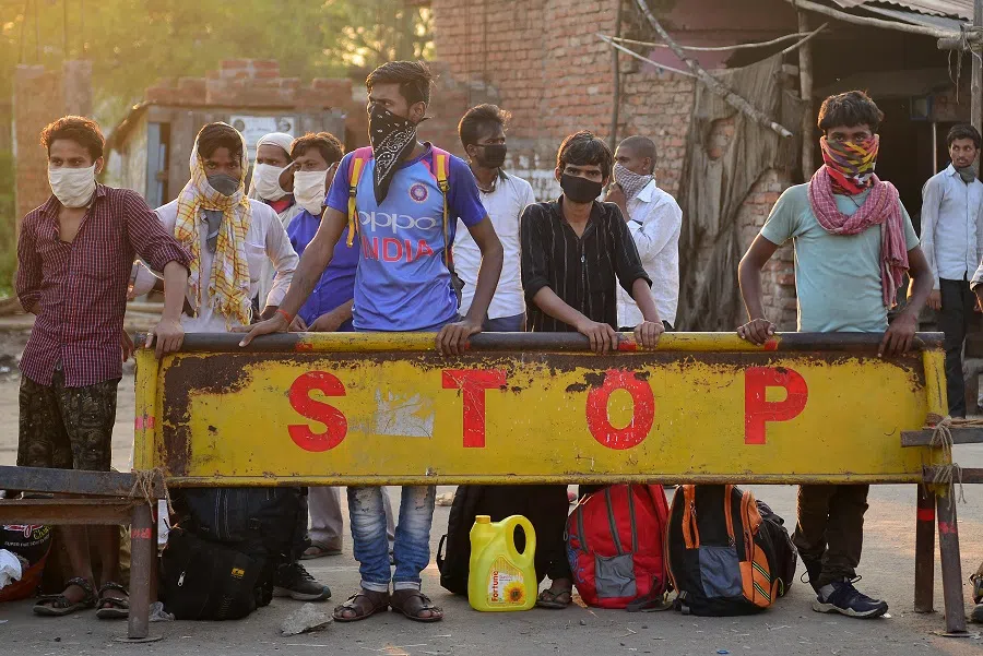 Migrant workers wait to board buses to reach their hometowns after the government eased a nationwide lockdown as a preventive measure against the Covid-19 coronavirus, on the outskirts of Allahabad, India, on 12 May 2020. (Sanjay Kanojia/AFP)