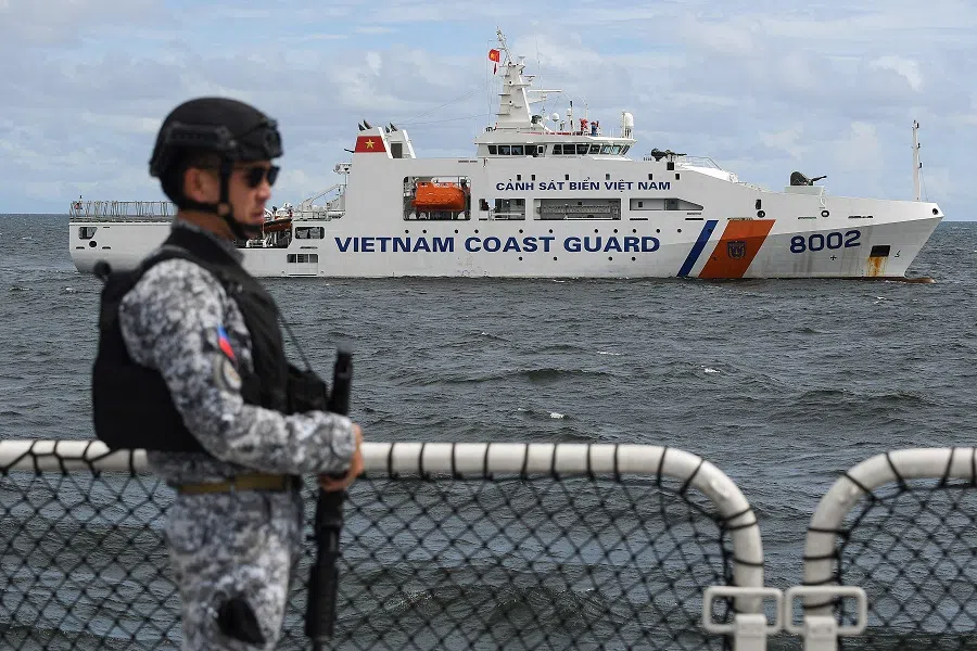 A member of the Philippine Coast Guard personnel stands guard aboard the Gabriela Silang ship as a Vietnamese Coast Guard ship sails past during a joint maritime exercise off Bataan in the disputed South China Sea on 9 August 2024. (Ted Aljibe/AFP)