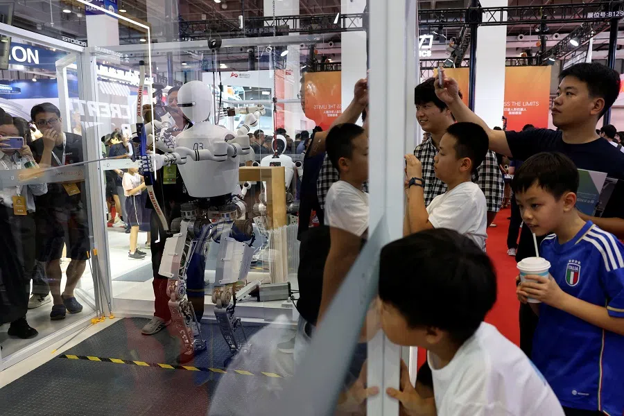 Visitors watch as a humanoid robot demonstrates its archery skills at the Institute of Automation, Chinese Academy of Sciences booth, during the World Robot Conference in Beijing, China, 21 August 2024. (Florence Lo/Reuters)