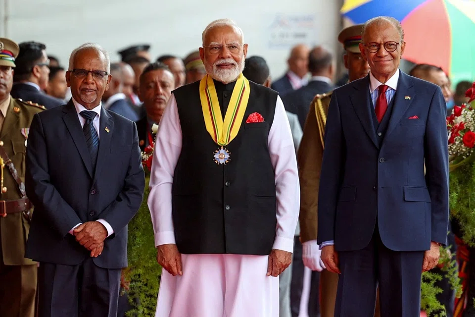 In this handout photograph taken on 12 March 2025 and released by the Indian Press Information Bureau (PIB), India’s Prime Minister Narendra Modi (centre) poses with his Mauritian counterpart Navinchandra Ramgoolam (right) during the National Day celebrations of Mauritius in Port Louis. (Indian Press Information Bureau/AFP)