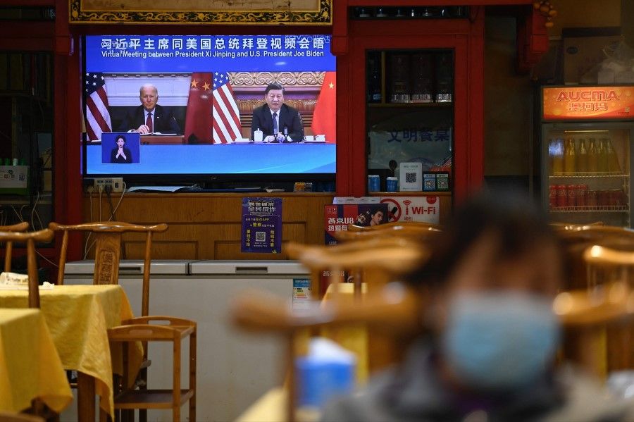 A television screen shows a news programme about a virtual meeting between Chinese President Xi Jinping and US President Joe Biden at a restaurant in Beijing on 16 November 2021. (Jade GaoAFP)