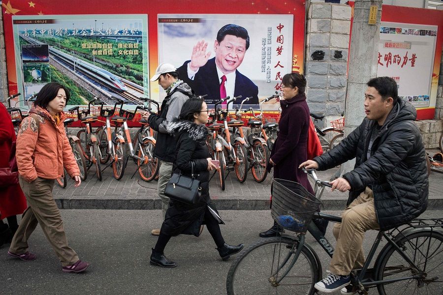 In this file photo taken on 12 March 2018, a propaganda poster showing China's President Xi Jinping is displayed on a wall in Beijing, China. (Nicolas Asfouri/AFP)
