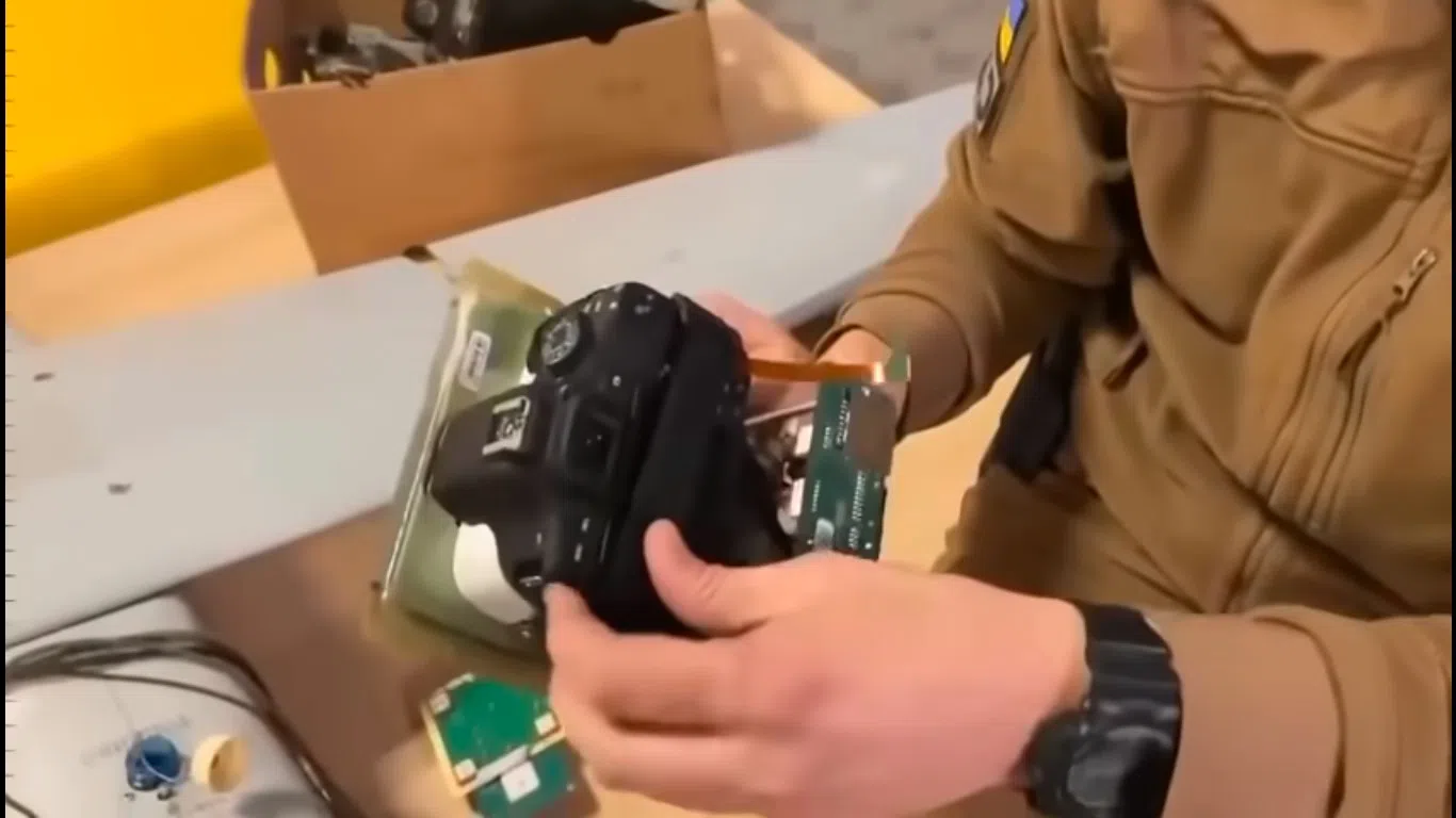 A screengrab of a video showing a soldier disassembling an Orlan-10 drone to reveal a Canon DSLR camera taped in place. (Internet)