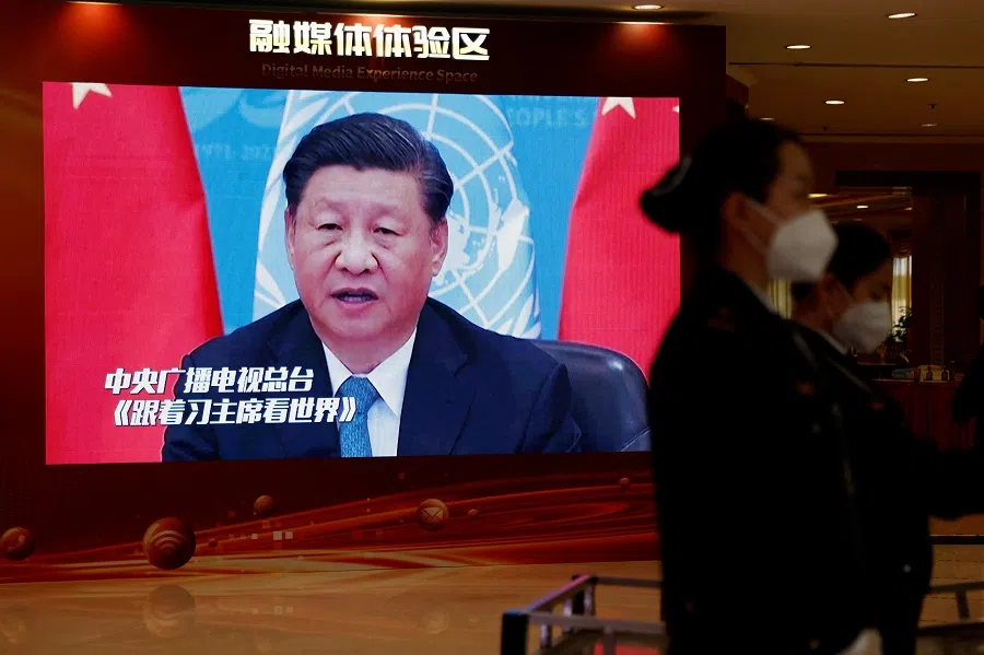Staff members wearing face masks stand near a screen displaying an image of Chinese President Xi Jinping, inside a media hotel for journalists covering the 20th Party Congress in Beijing, China, 19 October 2022. (Tingshu Wang/Reuters)