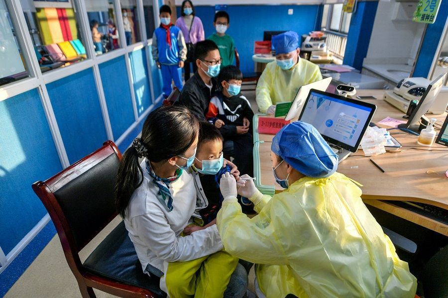A medical worker administers a dose of a Covid-19 vaccine to a child in Huzhou, Zhejiang province, China, on 26 October 2021. (China Daily via Reuters)