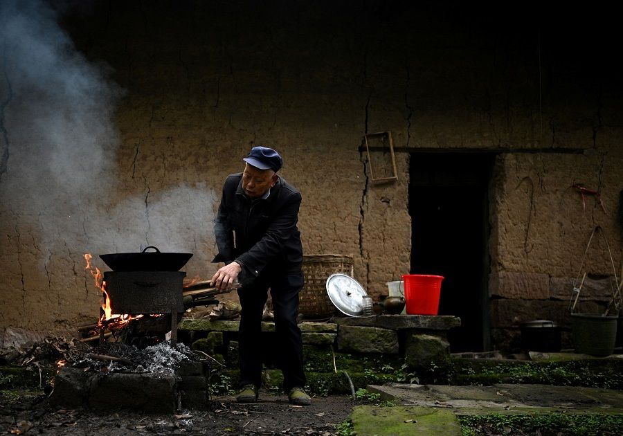 This photo taken on 29 November 2020, shows a man cooking a meal in front of his house in Zhongba, a small island near Chongqing, China. (Noel Celis/AFP)