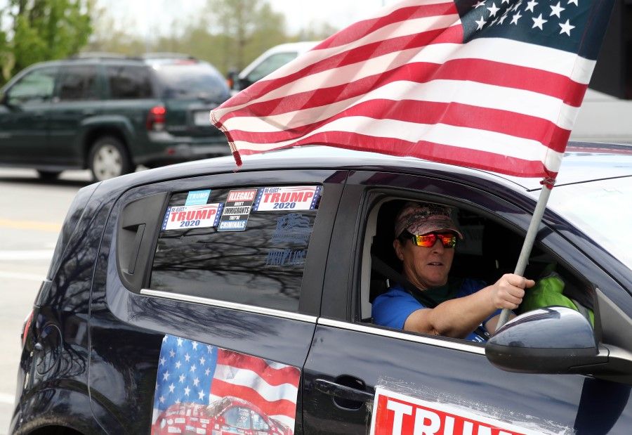 A Trump supporter waves an American flag during a protest at the Country Club Plaza against social distancing measures, April 20, 2020 in Kansas City, Missouri. The US state of Missouri has sued China's leadership over the coronavirus, prompting an angry rebuke from Beijing April 22, 2020 over the "absurd" claim. Missouri is seeking damages over what it described as deliberate deception and insufficient action to stop the pandemic. (Jamie Squire/AFP)