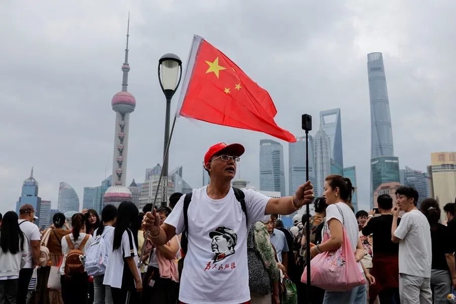 A person waves a Chinese flag while recording a video of himself at the Bund, with the Lujiazui financial district in the background, on China's National Day in Shanghai, China, 1 October 2026.