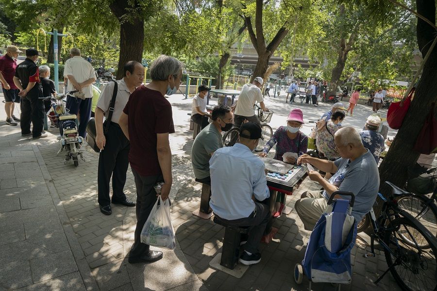 People wear protective masks while playing cards at a park in Beijing, China, on 6 July 2020. (Giulia Marchi/Bloomberg)