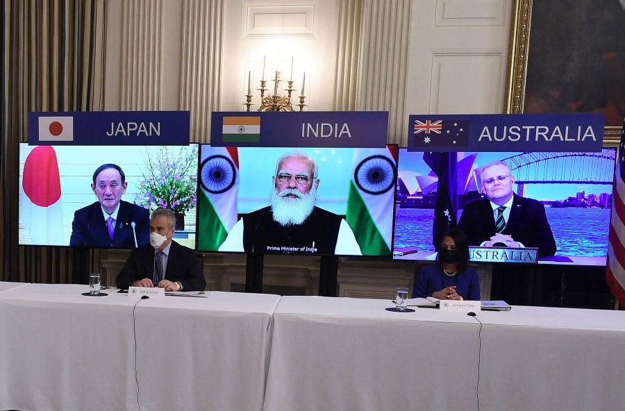 (On screens, left to right) Japanese Prime Minister Yoshihide Suga, Indian Prime Minister Narendra Modi and Australian Prime Minister Scott Morrison listen during a virtual meeting of Quad members Australia, India, Japan and the US, in the State Dining Room of the White House in Washington, DC, on 12 March 2021. Seated are counsellor to the president Jeff Zients (L) and national security council senior director for South Asia Sumona Guha. (Olivier Douliery/AFP)