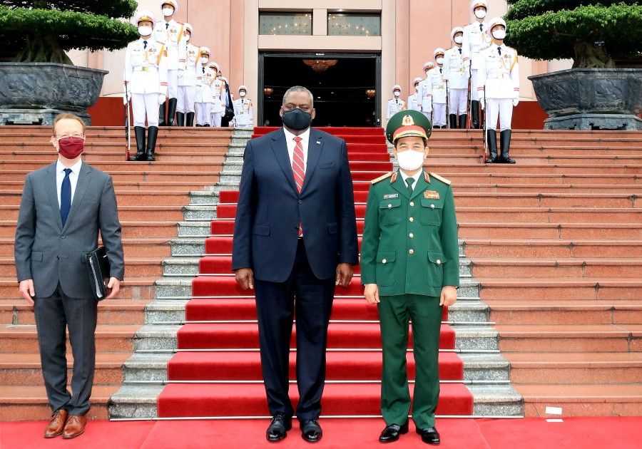 This picture taken and released by the Vietnam News Agency on 29 July 2021 shows US Defence Secretary Lloyd Austin (centre) and Vietnam's Defence Minister Phan Van Giang (right) posing for a photograph during a welcoming ceremony in Hanoi. (STR/Vietnam News Agency/AFP)