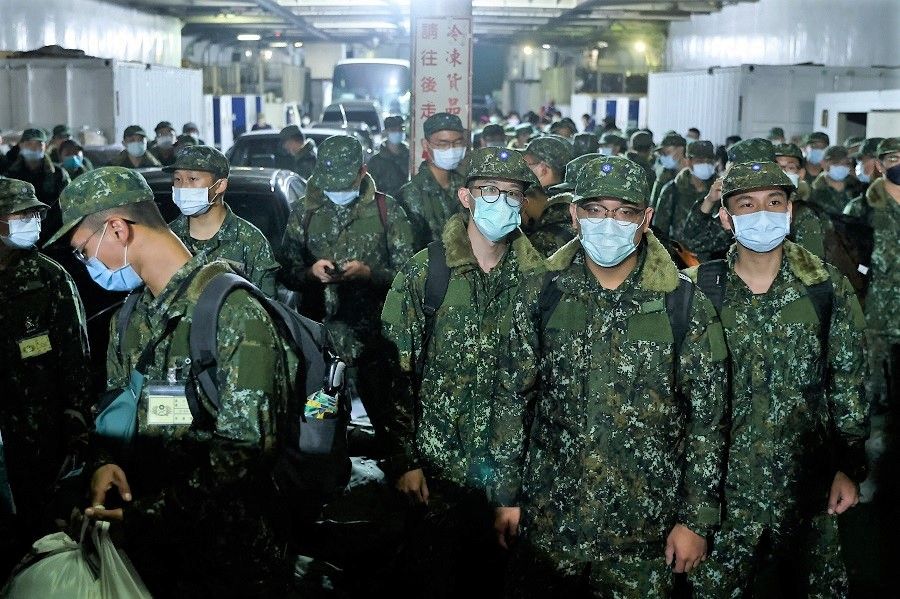 A group of soldiers who finished a month of training wait to depart from the ferry, and is about to finish the rest of their three-month mandatory military service in Nangan, Matsu, Taiwan, 17 March 2022. (Ann Wang/Reuters)