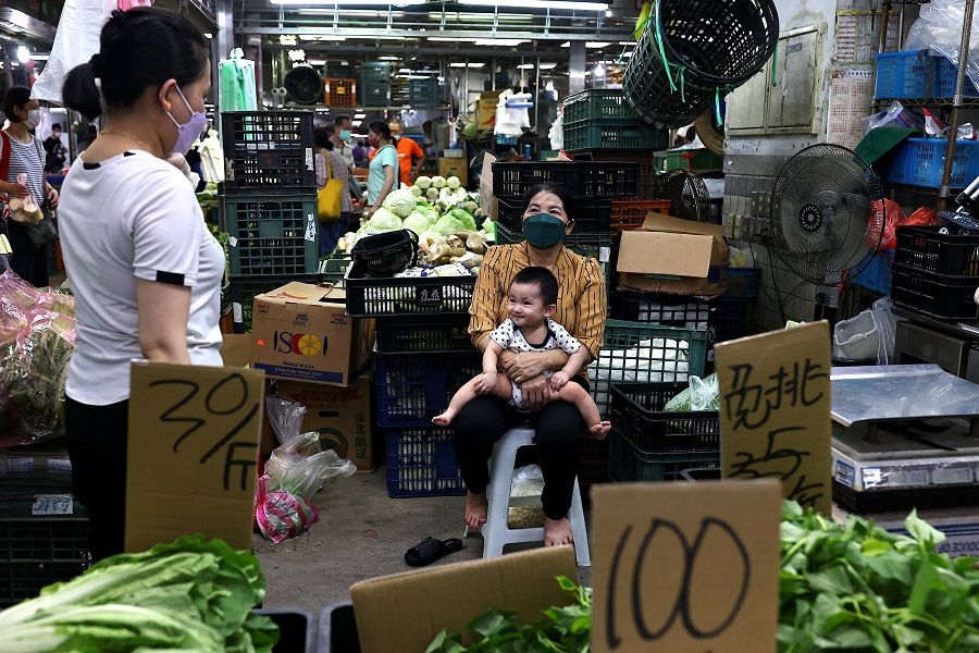 A family stands at their vegetable stall in a market in Taipei, Taiwan, 4 August 2022. (Ann Wang/Reuters)