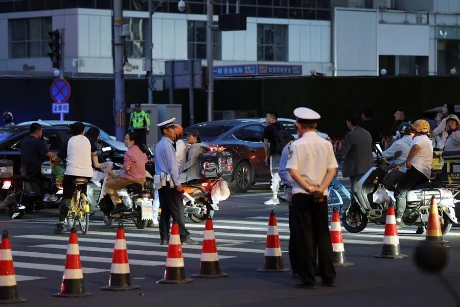 Police officers keep watch at a junction near CITIC Tower, also known as China Zun, where damage is visible on a high floor of the exterior, in Beijing, China, on 26 June 2026.