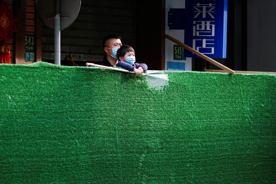 A resident and a child look over a barrier at a closed residential area during lockdown, amid the Covid-19 outbreak, in Shanghai, China, 18 May 2022. (Aly Song/Reuters)