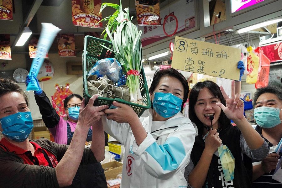 This photo taken on 23 November 2022 shows independent Taipei mayoral candidate Huang Shan-shan (centre) posing with a basket of "lucky vegetables" received by supporters during an election campaign at the Huannan Market in Taipei, Taiwan. (Sam Yeh/AFP)