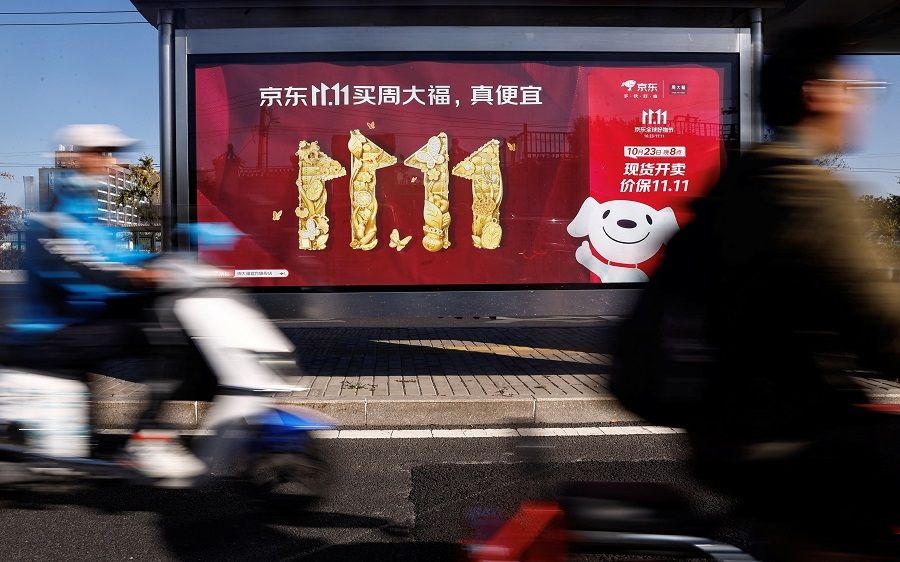 People ride on a scooter past a JD.com advertisement promoting the Singles' Day shopping festival, in Beijing, China, on 26 October 2023. (Tingshu Wang/Reuters)
