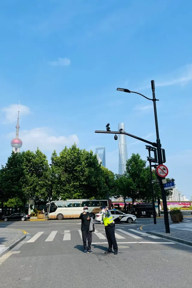 A security officer directs a pedestrian on a street in Shanghai, China.