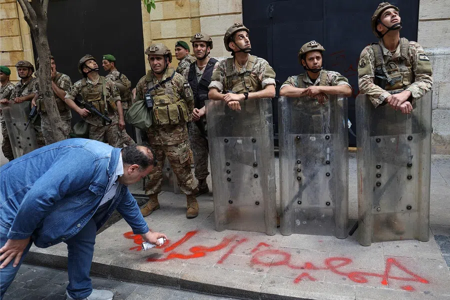 A Lebanese protester sprays a slogan on a sidewalk during a demonstration called for by the banks depositors committee against monetary policies, on 9 May 2023. (Anwar Amro/AFP)