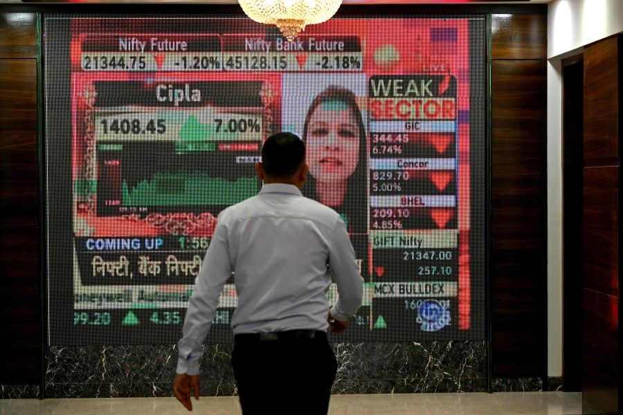 A man walks past a digital display inside the Bombay Stock Exchange (BSE) building in Mumbai on 23 January 2024. (Indranil Mukherjee/AFP)