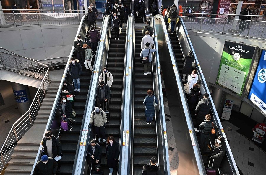 People wearing face masks use escalators at Seoul Station in Seoul, South Korea, on 30 January 2023. (Jung Yeon-je/AFP)