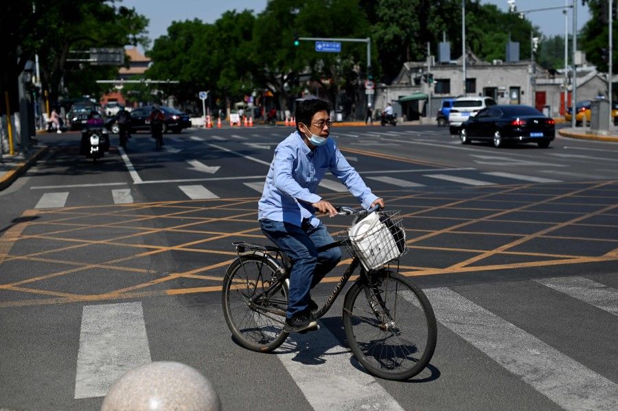 A man rides his bicycle along a road in Beijing on 17 May 2022. (Wang Zhao/AFP)