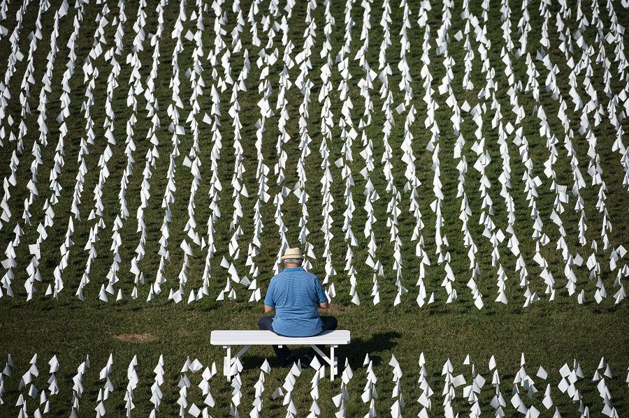 In this elevated view, a man sits on a bench along the flags of the 'In America: Remember' public art installation near the Washington Monument on 19 September 2021 in Washington, DC, US. (Al Drago/Getty Images/AFP)