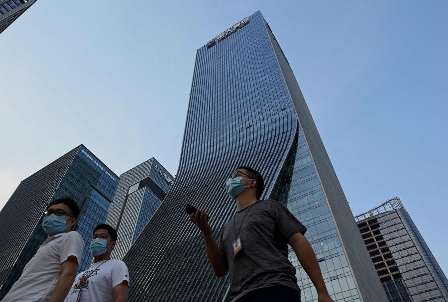 People walk in front of the Evergrande headquarters in Shenzhen, China's southern Guangdong province on 15 September 2021. (Noel Celis/AFP)
