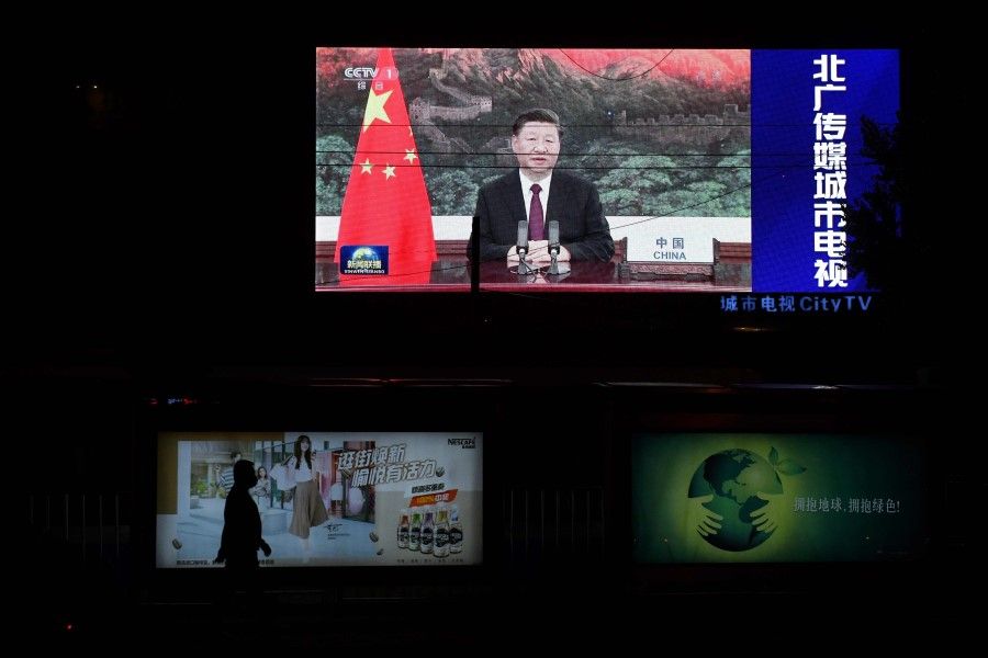 In this file photo taken on 22 September 2020, an image of Chinese President Xi Jinping appearing by video link at the United Nations 75th anniversary is seen on an outdoor screen as a pedestrian walks past below in Beijing. (Greg Baker/AFP)