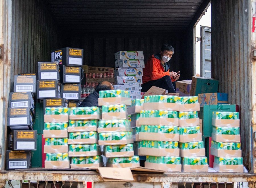 A community worker wearing a protective mask sits on a truck loading daily supplies in a compound during a Covid-19 lockdown in Pudong district in Shanghai, China, on 14 April 2022. (Liu Jin/AFP)