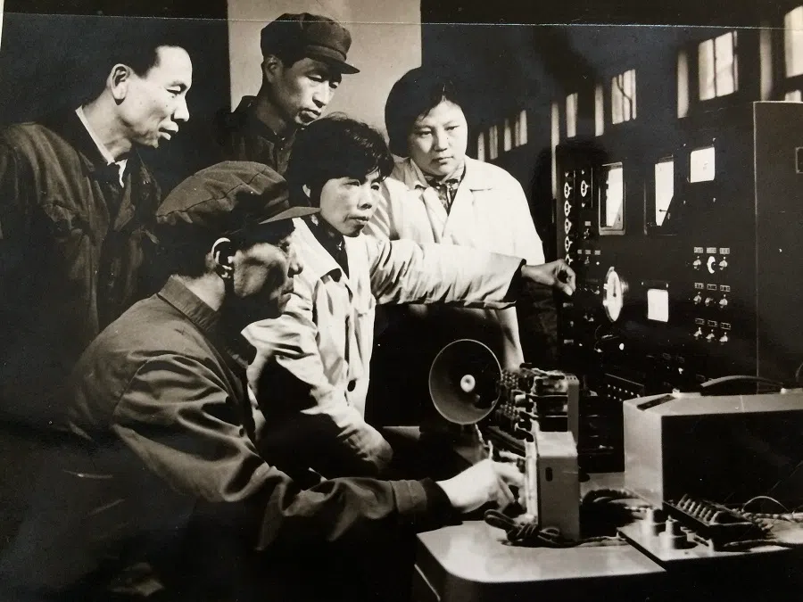 From an interviewee’s family collection: in this historical photo from the mid-1970s, a group of workers gathers around a newly assembled control machine, attentively learning its operation under the expert guidance of a master technician, often referred to as shifu. 