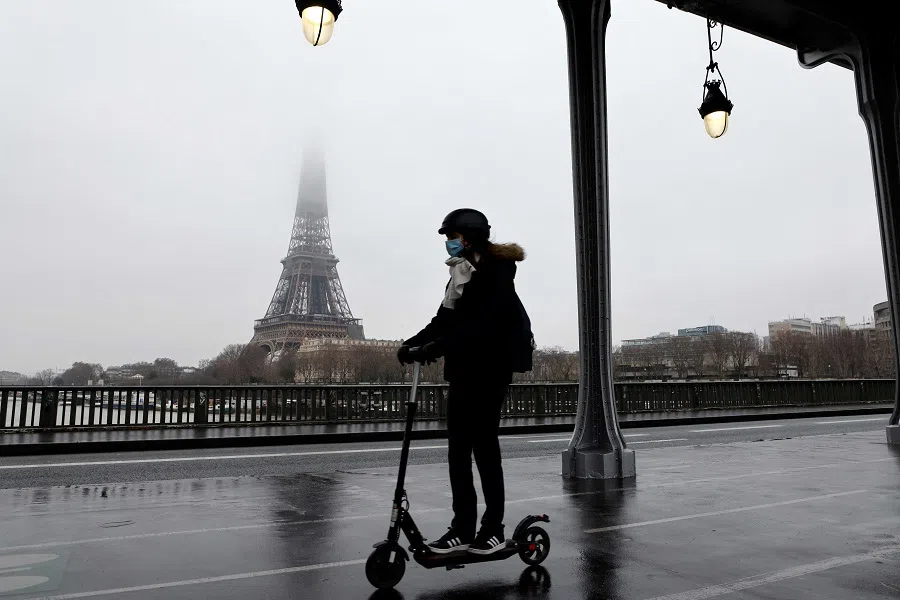 In this file photo taken on 27 January 2021, a woman rides a scooter in Paris, France, in front of the Eiffel Tower. (Ludovic Marin/AFP)