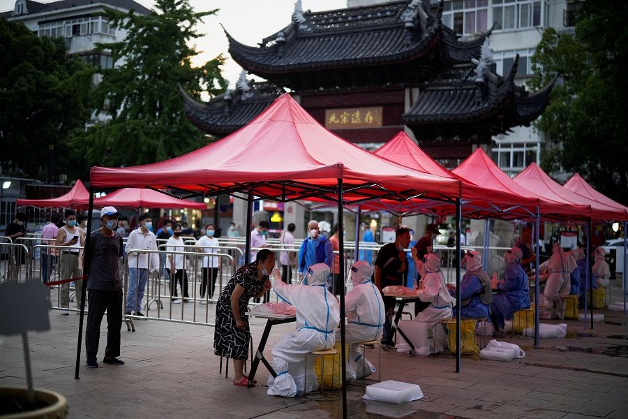 People line up to get tested for Covid-19 at a nucleic acid testing site, in Shanghai, China, 12 July 2022. (Aly Song/Reuters)