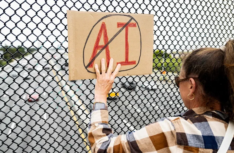 A person holds up a sign on a pedestrian bridge during a nationwide protest against AI data center expansion in Berkeley, California, on 18 July 2026.