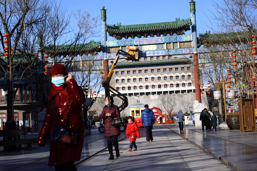 People walk at Qianmen Street, in Beijing, China, 25 January 2022. (Tingshu Wang/Reuters)