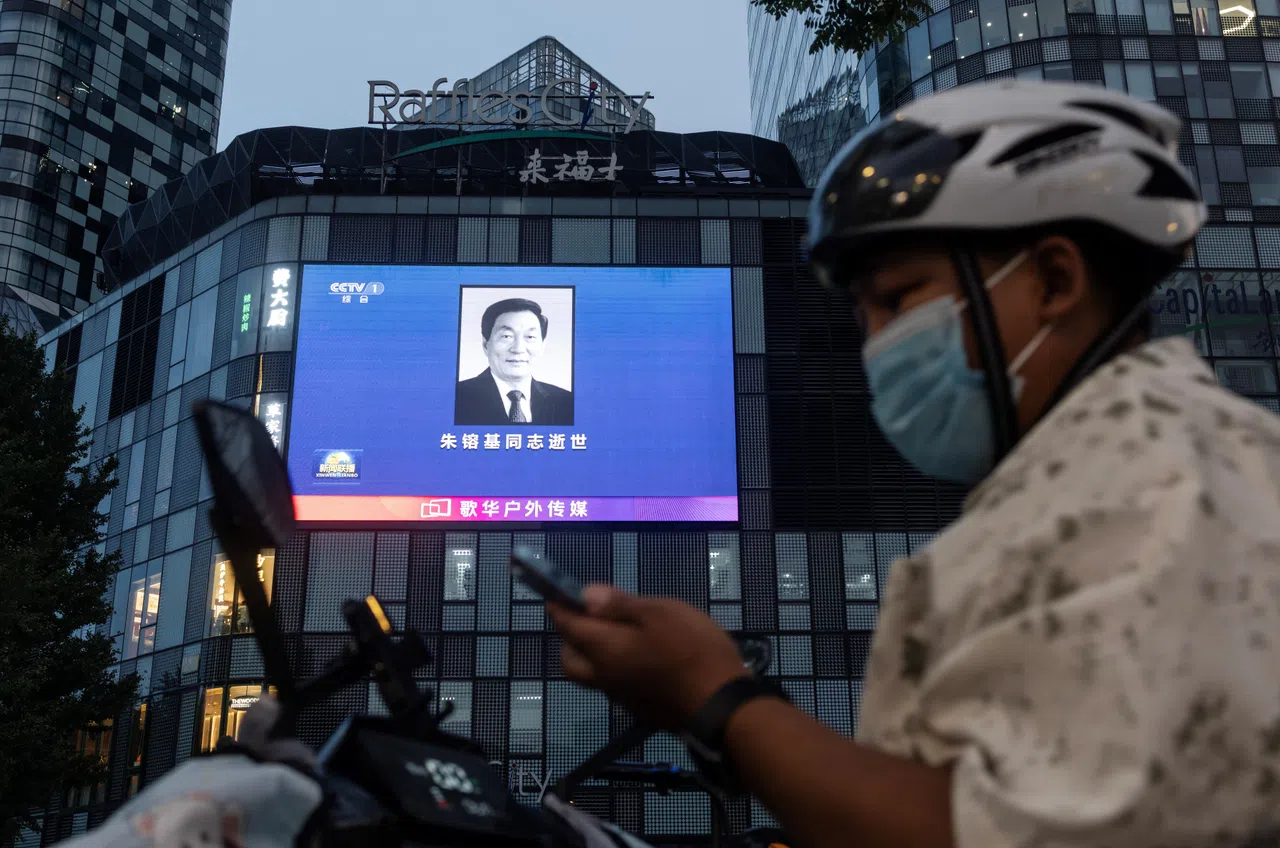 A man uses his smartphone next to a giant screen on a shopping mall broadcasting a portrait of former Chinese Premier Zhu Rongji who passed away on 12 August, in Beijing, China, on 12 August 2026.
