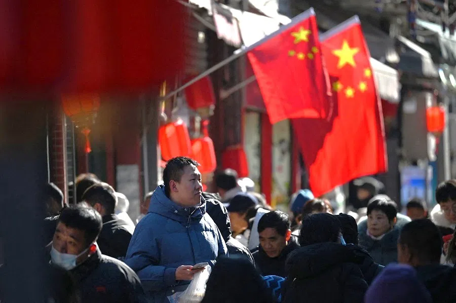 People walk below Chinese flags in a shopping street in Beijing, China, on 3 February 2025.