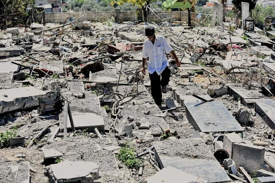 A man walks between damaged headstones, destroyed in Israeli military strikes, at the cemetery in the southern Lebanese village of Srifa on 24 June 2026.