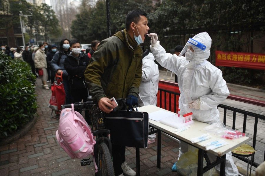 A resident (left) undergoes a nucleic acid test for Covid-19 in Wuhan in China's central Hubei province on 22 February 2022. (AFP)