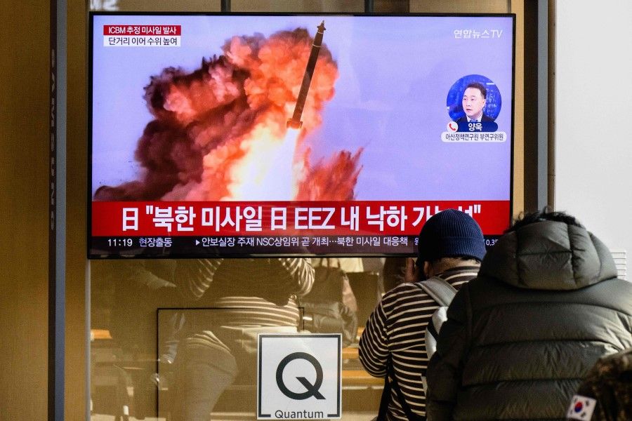 People sit near a television showing a news broadcast with file footage of a North Korean missile test, at a railway station in Seoul on 18 November 2022. (Anthony Wallace/AFP)