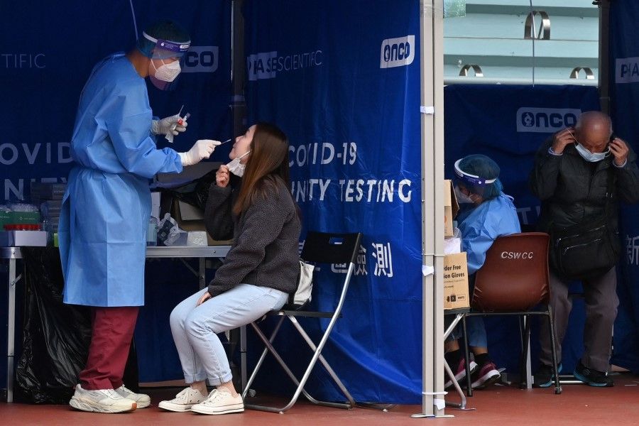 People are tested at a mobile specimen collection station for Covid-19 in Hong Kong's Prince Edward district on 8 February 2022. (Peter Parks/AFP)
